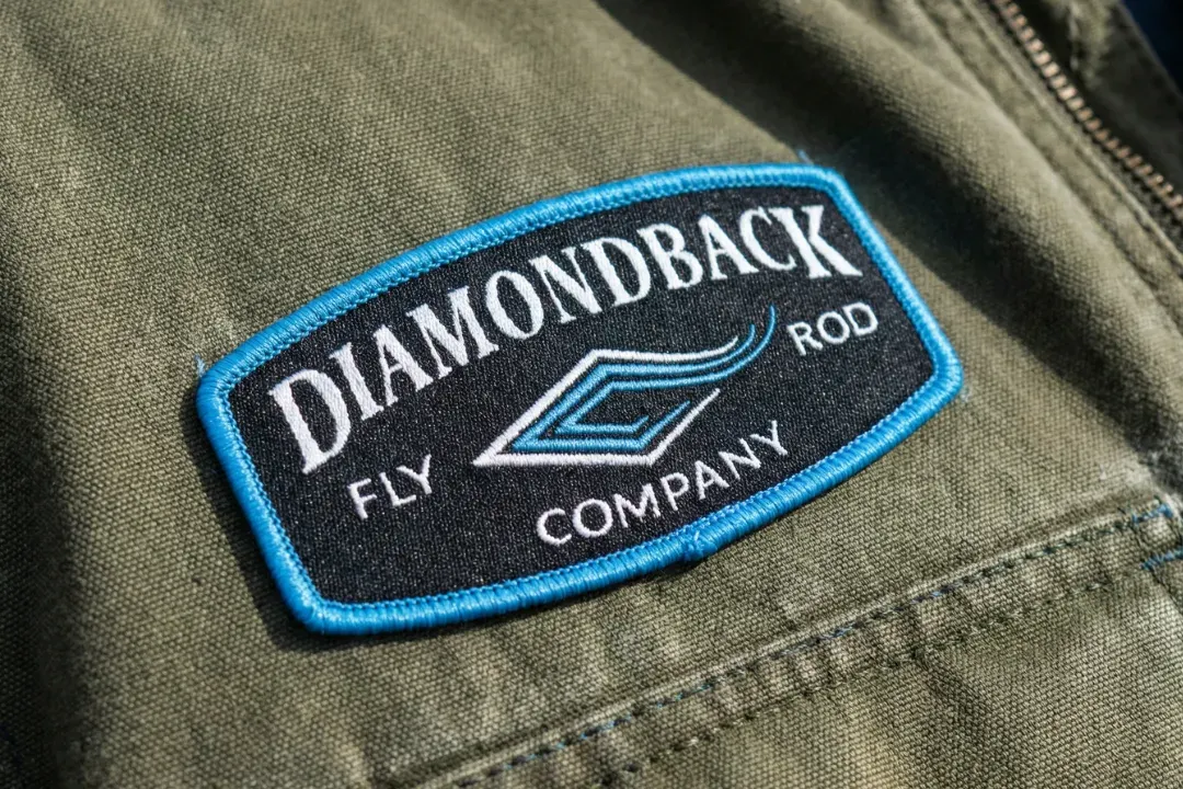 Close up image of an embroidered patch with trees and pink background
