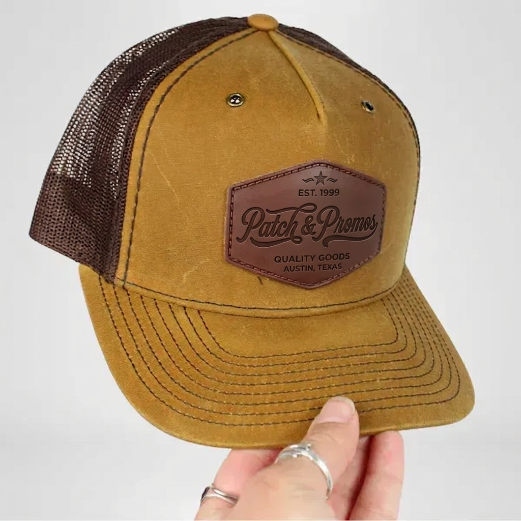 Custom brown trucker hat with embossed leather Patch & Promos patch shown in hand
